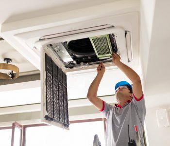 Electrician fitting air conditioning to office interior
